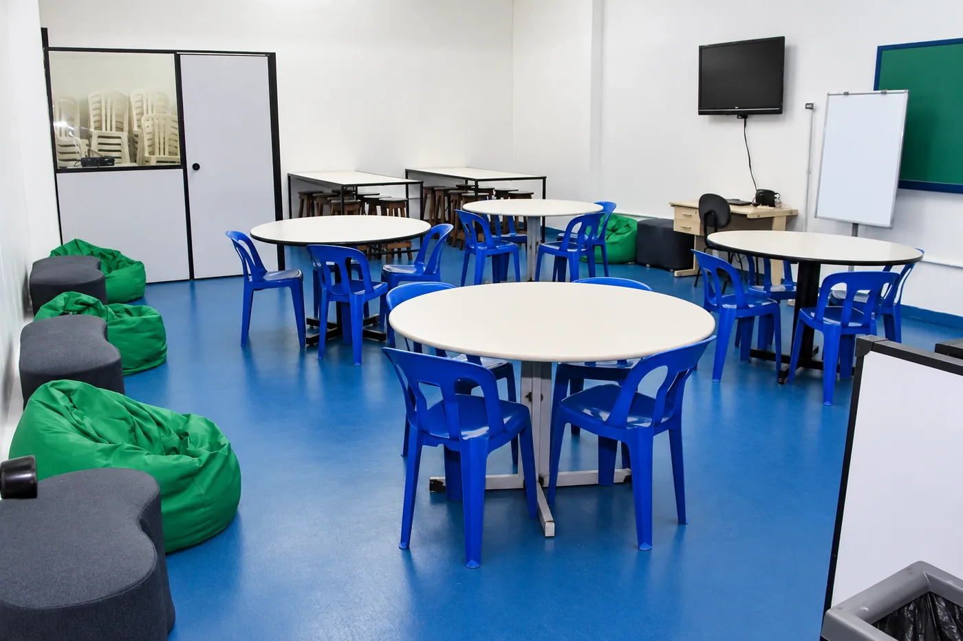 Sala multiuso com mesas e pufes